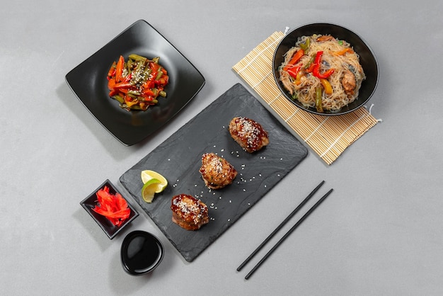 Uma variedade de comida asiática em um fundo escuro de concreto frango teriyaki em um fundo cinza com ses