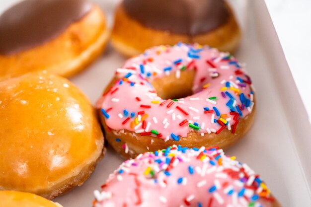 Uma variedade de donuts comprados em uma caixa de papel branco.