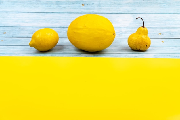 Uma variedade de frutas amarelas encontra-se em um fundo azul de madeira e um fundo amarelo