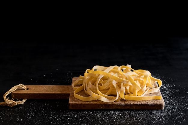 Uma variedade de massas tagliatelle cruas caseiras italianas em uma placa de corte