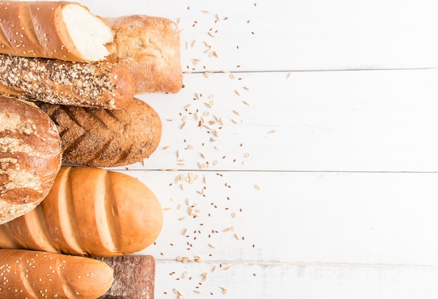 Uma variedade de pão fresco e delicioso em um fundo branco de madeira de tábuas com sementes de gergelim de linho aveia uma cópia do espaço