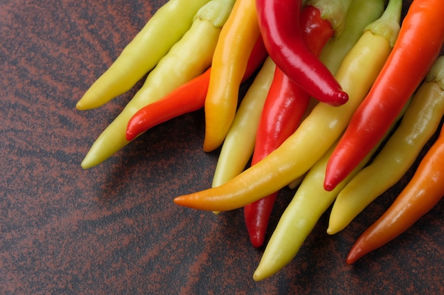 Uma variedade de pimenta amarga multicolorida em um prato de argila marrom macro fotografia
