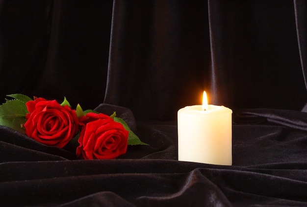 Uma vela acesa e uma rosa vermelha em um fundo preto