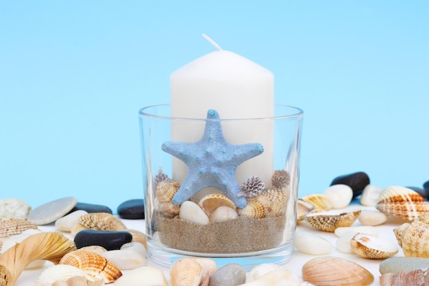 Uma vela com uma estrela do mar e conchas sobre a mesa.