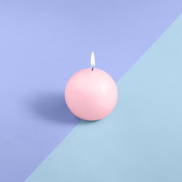 Uma vela redonda rosa em um fundo azul e roxo conceito mínimo layout isométrico quadrado