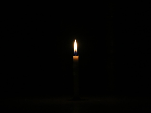 Uma vela romântica de romance perto do jantar. A luz é isolada no fundo preto.