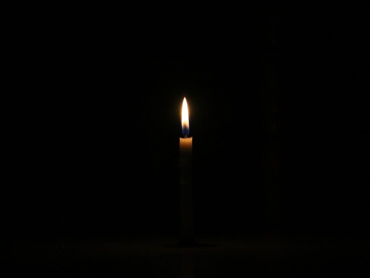 Uma vela romântica de romance perto do jantar. A luz é isolada no fundo preto.