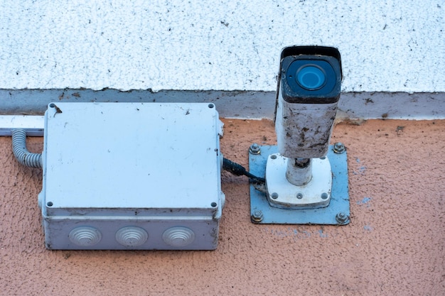 Uma velha câmera de vigilância suja coberta de poeira e teias de aranha instaladas na fachada do edifício em close-up sistemas de proteção de segurança e roubo