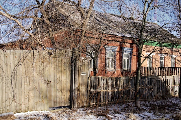 Uma velha casa de madeira e um portão de prancha na frente dela