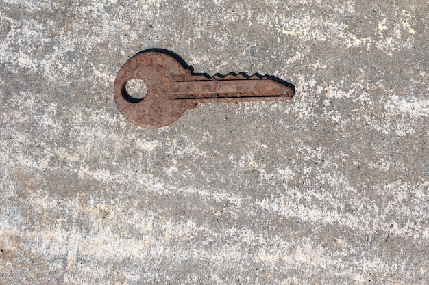 Uma velha chave enferrujada em um fundo cinza. fique em casa conceito. conceito abandonado e esquecido.