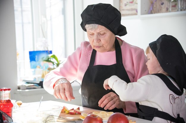 Uma velha com uma garotinha na cozinha preparando frutas para servir