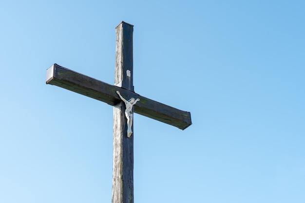 Uma velha cruz cristã de madeira contra um céu azul claro em um lindo dia de verão Uma estatueta de Jesus no centro da cruz A crucificação de Cristo A festa da Páscoa e Ressurreição