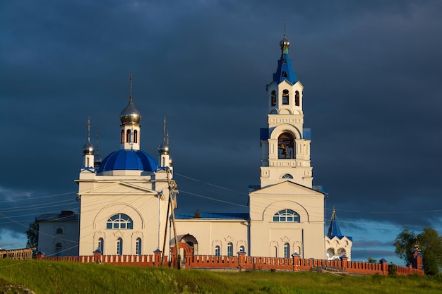 Uma velha igreja ortodoxa nas margens do rio sol e nuvens negras