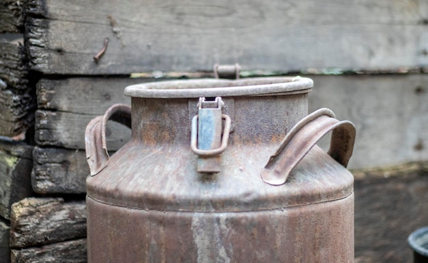 Uma velha lata de metal enferrujada no campo recipiente para transporte de leite líquido ou combustíveis líquidos com alças múltiplas banco de leite de forma cilíndrica com boca larga garrafa com tampa selada