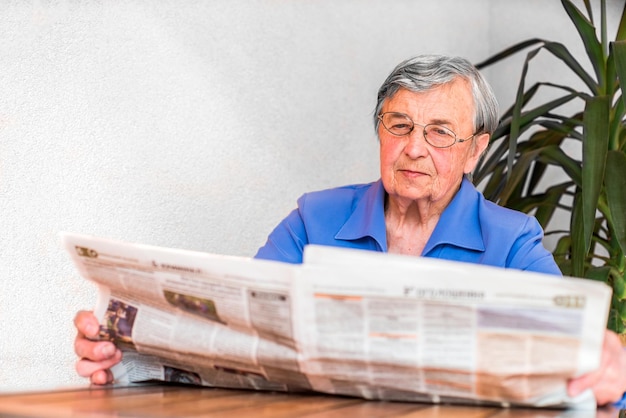 uma velha lê um jornal.