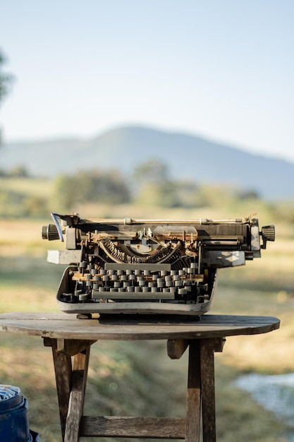 Foto uma velha máquina de escrever em uma mesa de madeira há um campo de arroz no fundo