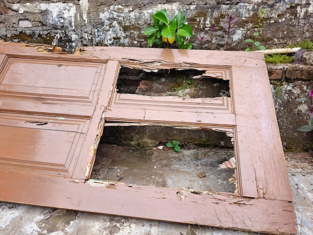 Foto uma velha porta de madeira quebrada apoiada contra uma velha parede de musgo