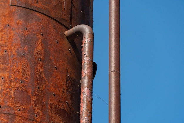 Uma velha torre de água enferrujada de metal Antiga tecnologia de produção processando secagem no complexo agroindustrial Silo vermelho no fundo do céu Construção metálica