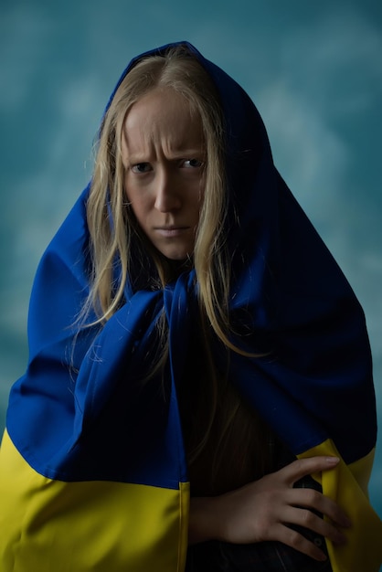 Uma verdadeira loira ucraniana está chateada com o mal e decepcionada durante a guerra com a bandeira ucraniana amarela e azul na cabeça Rússia atacou a Ucrânia em 24 de fevereiro de 2022