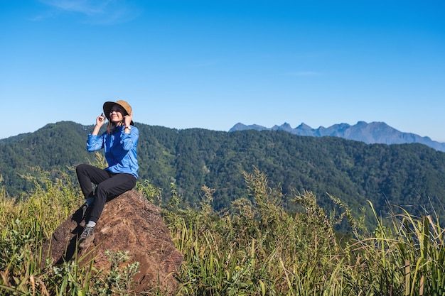 Uma viajante feminina caminhando e sentada no pico da montanha olhando uma bela vista