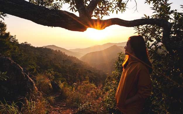 Foto uma viajante feminina em pé no pico da montanha e assistindo o nascer do sol da manhã
