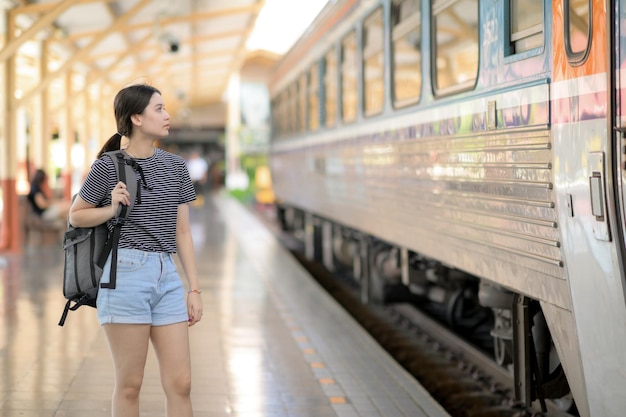 Uma viajante internacional feminina com uma mochila espera o trem