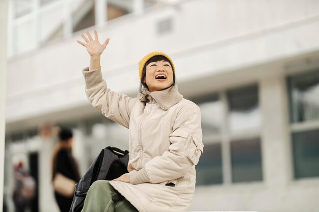 Uma viajante japonesa sentada na estação de trem e acenando para sua amiga