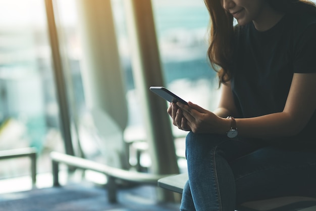 Uma viajante usando um telefone celular enquanto está sentada no aeroporto