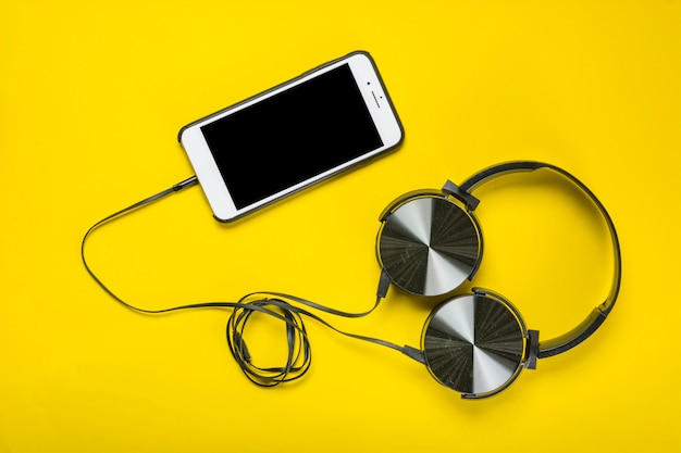 Uma visão aérea do fone de ouvido anexado com celular em fundo amarelo
