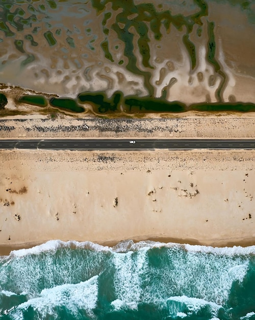 Uma vista aérea de uma praia com uma estrada que leva ao oceano.