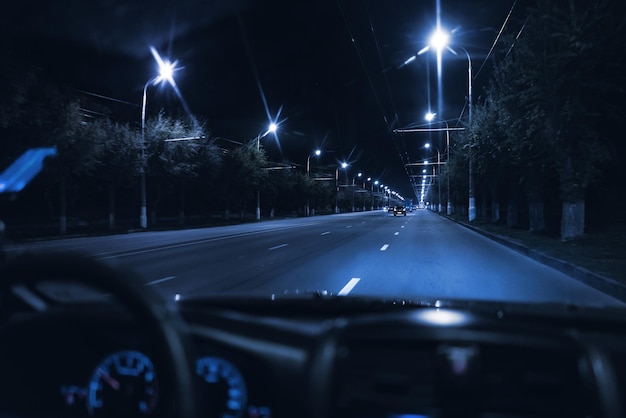 Uma vista de dentro do carro dirigindo à noite na estrada de tráfego da cidade