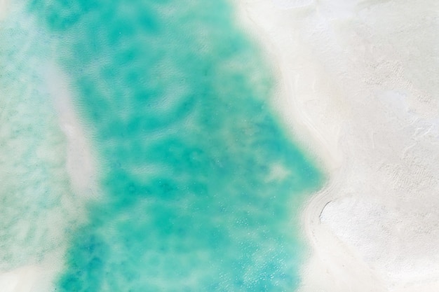 Uma vista do alto de uma praia tropical e ondas quebrando em uma praia tropical de areia dourada. as ondas do mar ondulam suavemente ao longo da bela praia de areia.