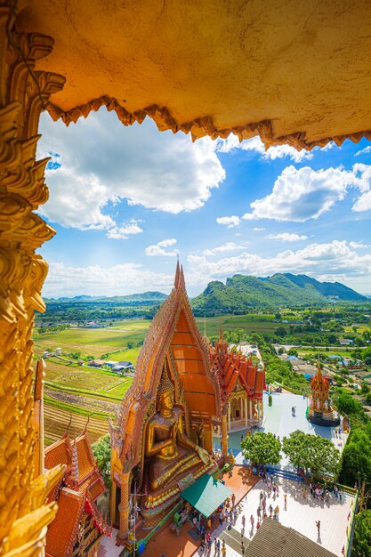 Uma vista do topo da estátua de Buda dourado do pagode com campos de arroz e montanhas