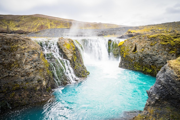 Uma vista fascinante da cachoeira Sigoldufoss, que desce pelos penhascos rochosos da Islândia