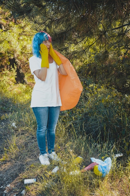 Foto uma voluntária com um rosto chocado limpando o ambiente da poluição plástica segurando um saco de lixo