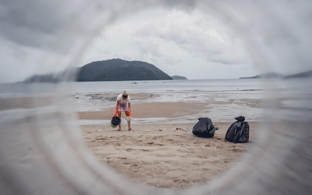 Uma voluntária ecologista limpa a praia à beira-mar de plástico e outros resíduos