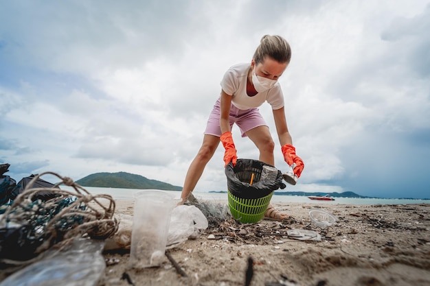 Uma voluntária ecologista limpa a praia à beira-mar de plástico e outros resíduos