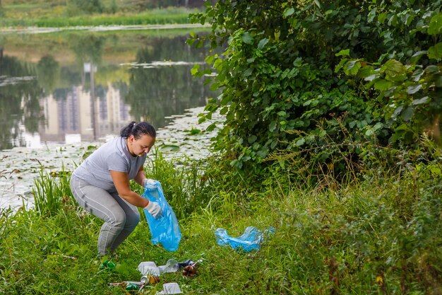 Uma voluntária remove lixo de um aterro próximo ao rio.