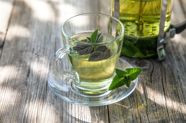 Uma xícara com chá de menta fresca e perfumada em uma mesa de madeira no jardim de verão