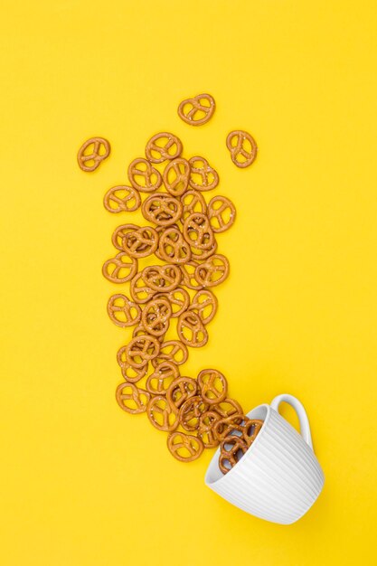 Foto uma xícara com pretzels efusos em um plano de fundo amarelo minimalista conceitual