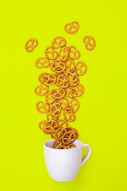 Foto uma xícara com pretzels efusos em um plano de fundo verde minimalista conceitual