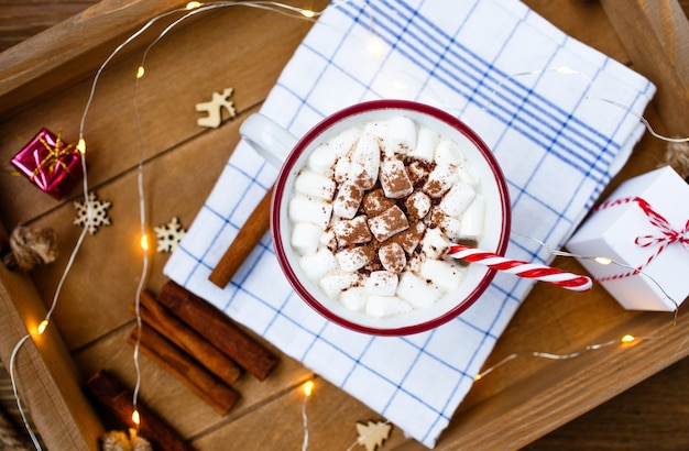 Uma xícara de bebida quente de Natal em um fundo de madeira em torno de um pau de canela e presentes de Natal.