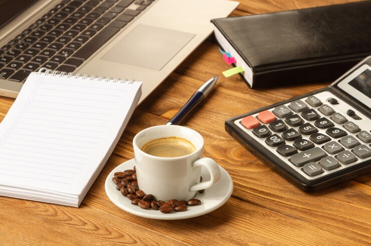 Uma xícara de bom café ajuda a trabalhar com documentos. Caderno, caneta, laptop, calculadora, documentos financeiros, uma xícara de café cappuccino em cima da mesa.
