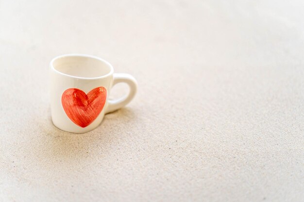 Uma xícara de café branca com um coração vermelho.