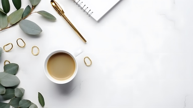 Uma xícara de café branca com uma folha de ouro está sobre uma mesa branca ao lado de uma planta.