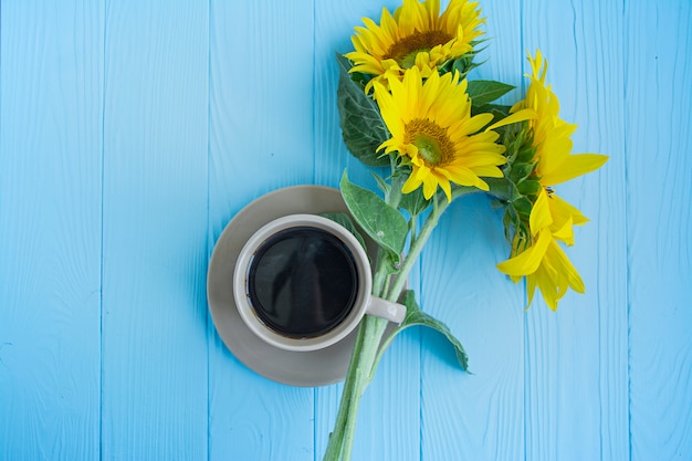 Uma xícara de café canela e girassol sobre um fundo azul.