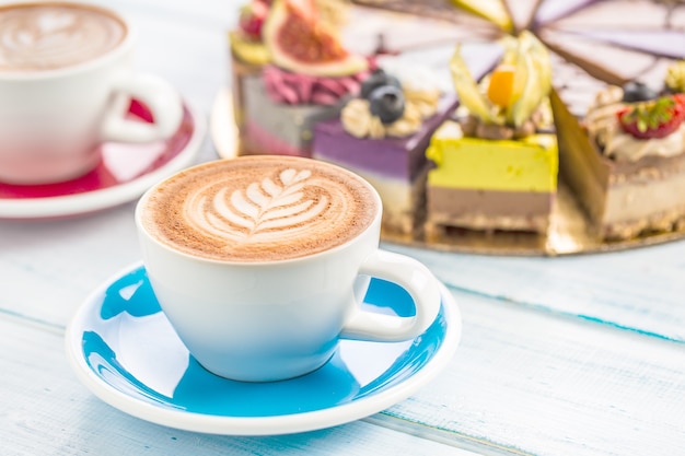 Uma xícara de café cappiciino de arte e mini bolos crus.