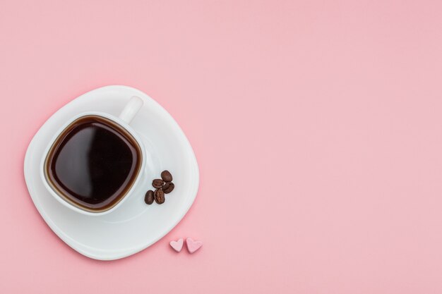 uma xícara de café com corações de marshmallow em fundo rosa. Conceito de humor matinal