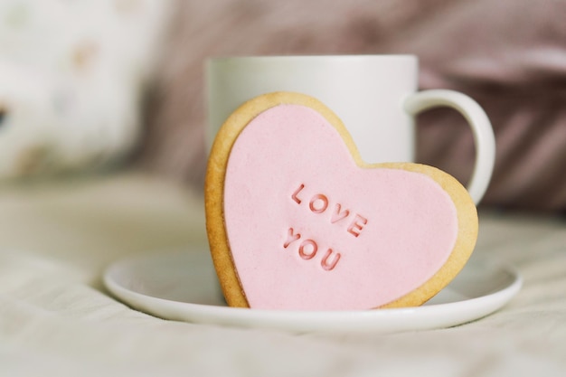 Uma xícara de café com deliciosos biscoitos com a inscrição te amo Comemorando o dia dos namorados em casa Conceito do dia dos namorados