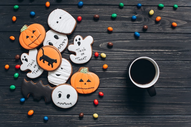 Foto uma xícara de café com doces de cores e pães de gengibre assustadores no halloween.